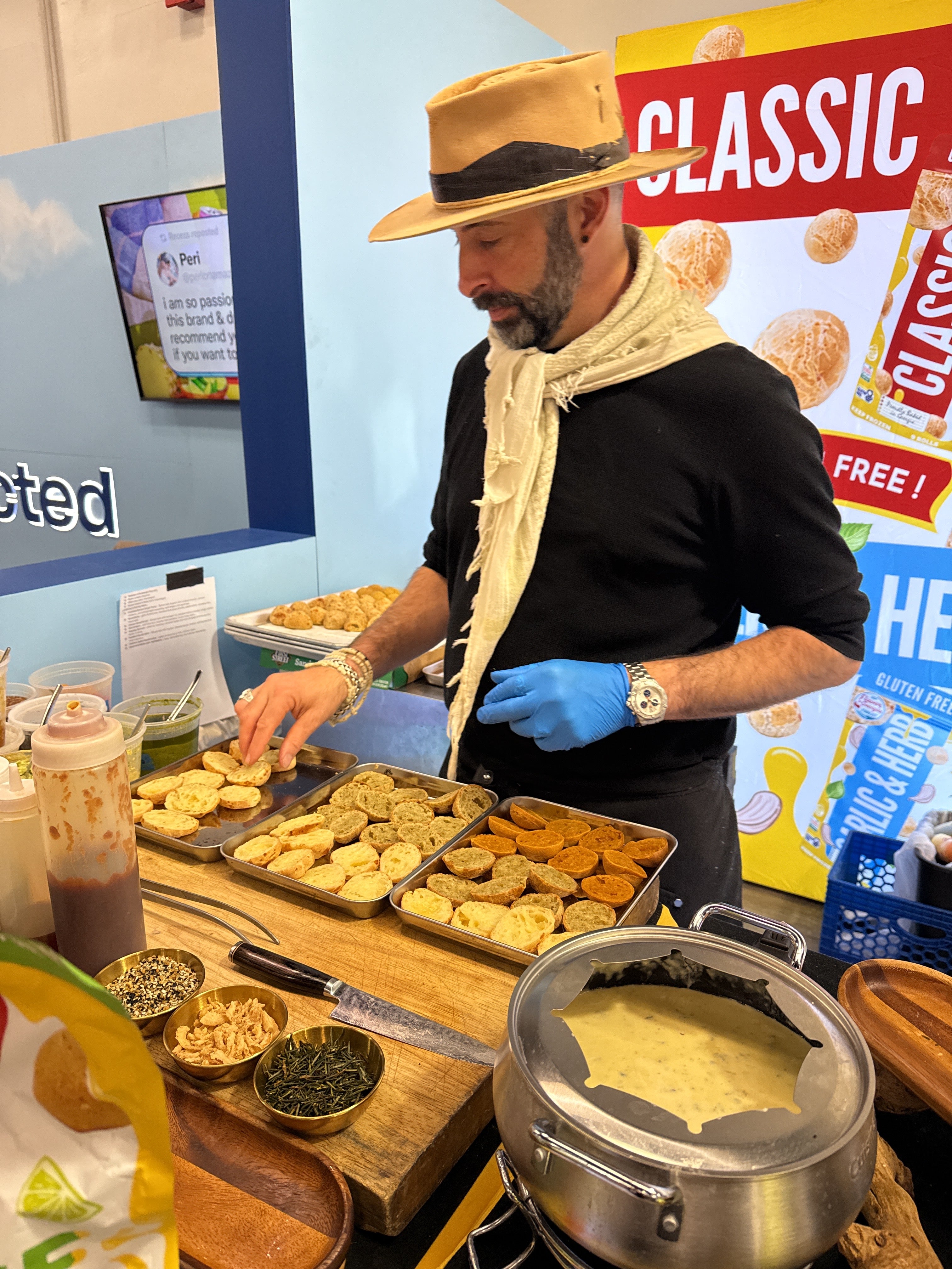 Person in a black shirt and blue gloves preparing food at a counter with various items including a pot  and cheese chef keven cheese bread rolls grain free, gluten free