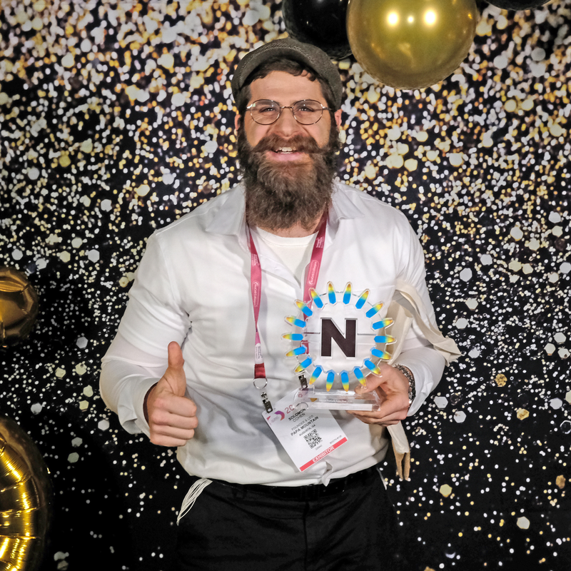 Solomon Cohen, founder of Papa Mountain, holding the 2026 NEXTY Award trophy at Natural Products Expo West for the brand's Sweet Potato & Herb Bread Rolls, special diets awards
